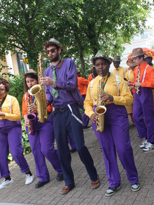 A New Orleans style jazz band are performing as they walk down the street.