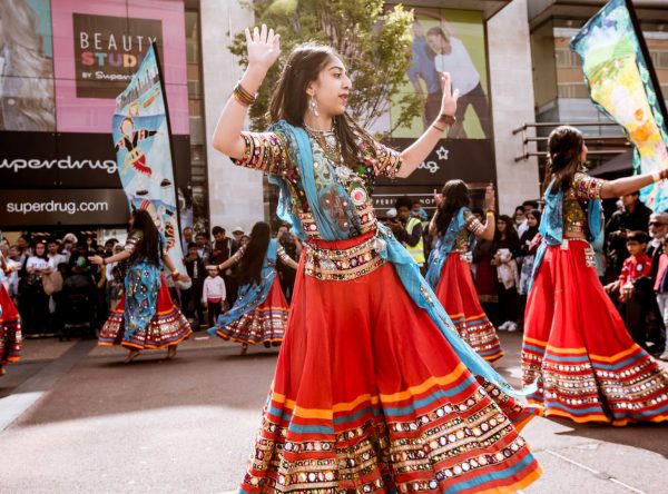 A young performer in traditional Asian dress dancing on a city centre square.