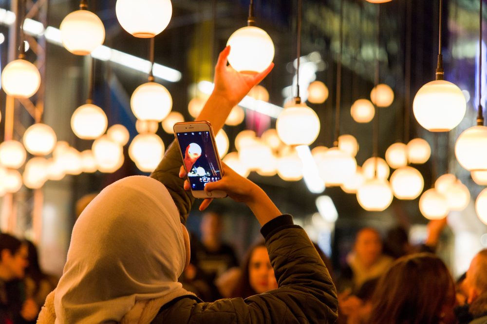 An audience member taking a picture of a light bulb which is part of a light installation.