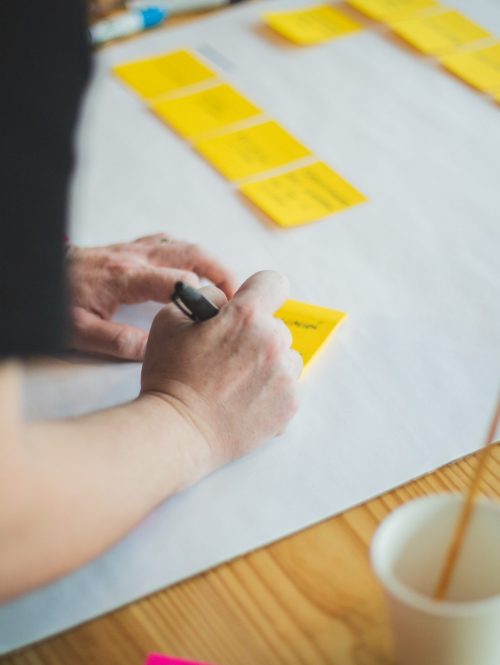 A close-up photograph of someone writing on a post it note.