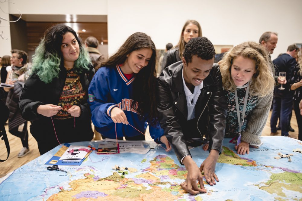 Audiences looking and writing on a world map.