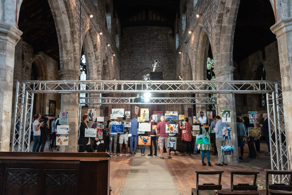 An art exhibition is suspended from scaffolding in an old church.