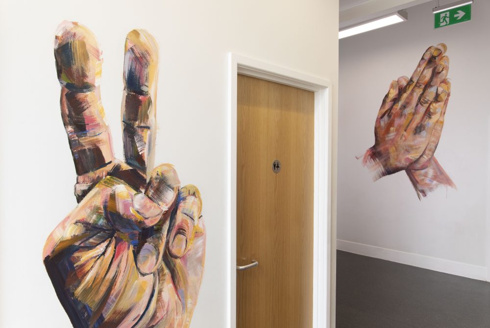 Two large-scale hands painted onto the walls of the toilet area of New Walk Museum.