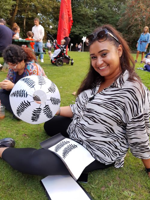 A woman sitting on a grass lawn in a park during creative workshops.