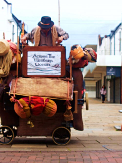 A young child stands in front of a puppetry performance in a shopping centre