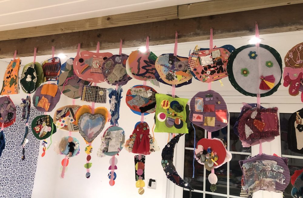 A number of giant sequins hanging next to each other from the ceiling in the artist's workshop.