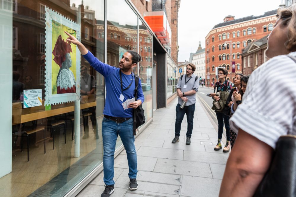 An artwork in the window front is explained to audiences looking at the artwork.