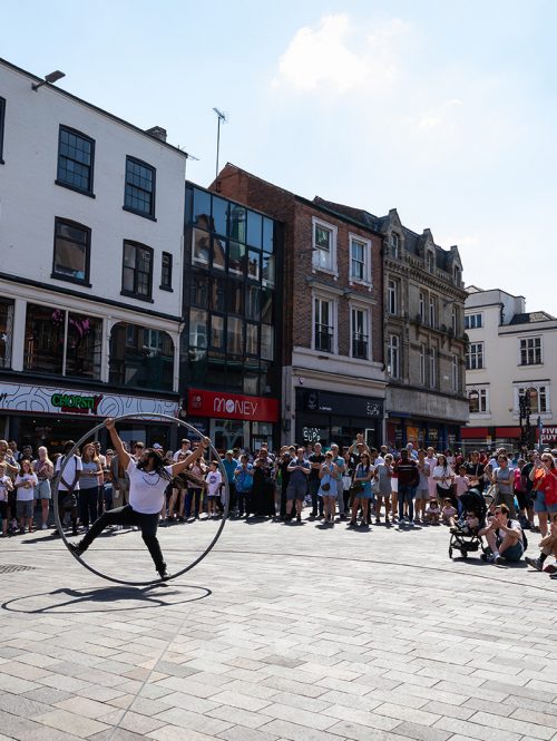 A man performs in front of an audience on a Cyr wheel.