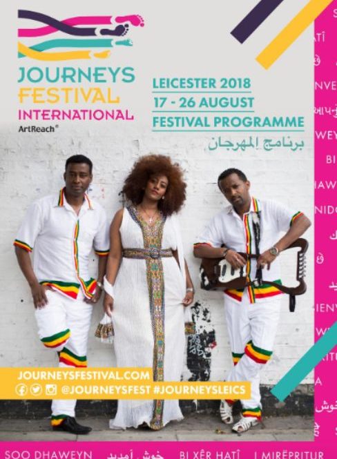 Three musicians wearing traditional Ethiopian clothing lean against a white wall.