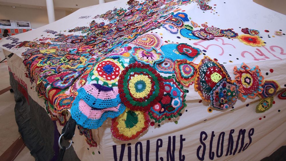 Colourful knitted circles decorate a refugee shelter.
