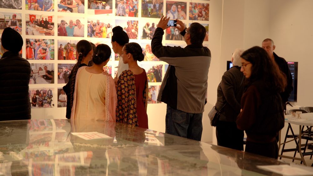 A group of young peoople are looking at and photographing an exhibition.