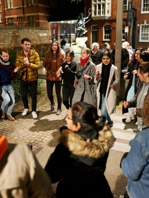 A group of people dancing outdoors at night as part of The Midnight Run in Leicester in March 2022.