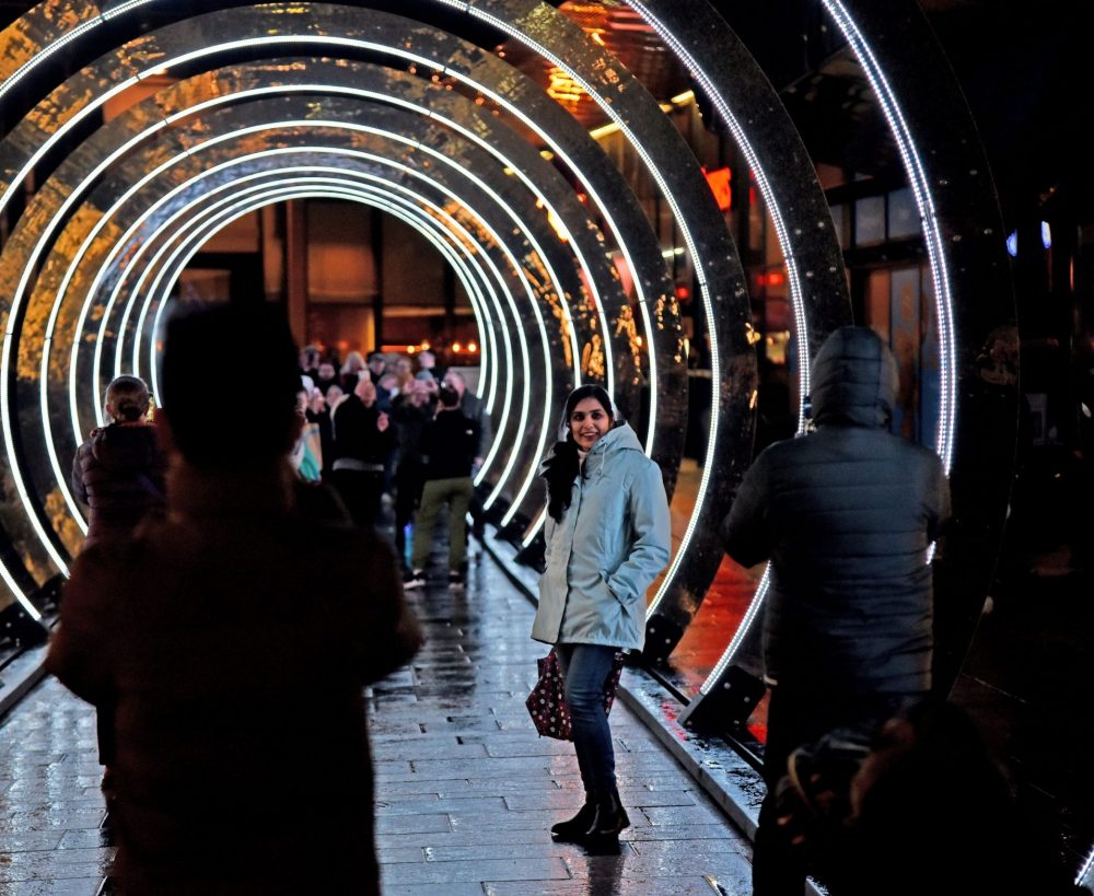 Audience members standing in a light installation that consists of a series of enlightened rings that you walk through.