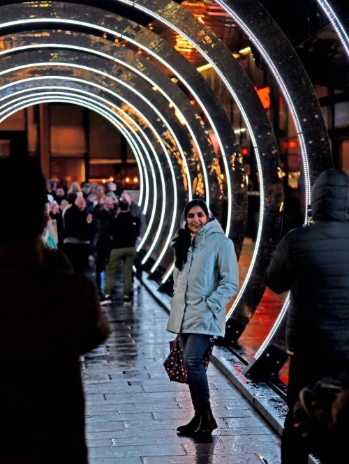 Audience members standing in a light installation that consists of a series of enlightened rings that you walk through.