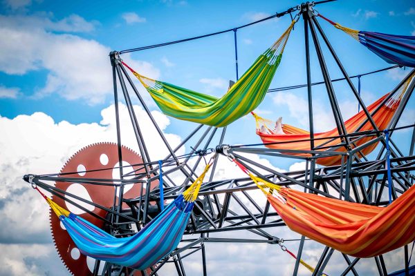 A number of hammocks attached to a rotating metal frame.