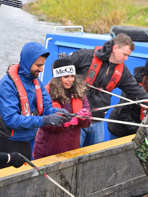 A group of people picking litter from a boat.