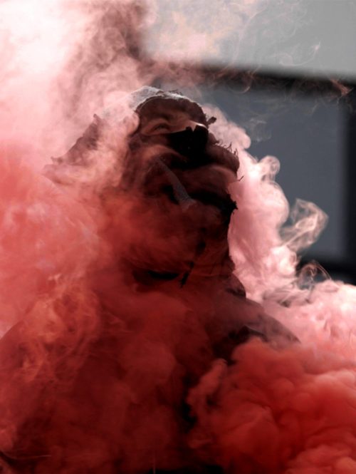 A performer surrounded by dense red smoke.