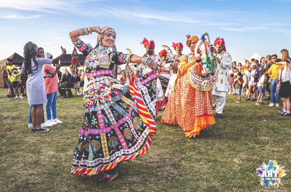 A group of Indian dancers in traditional costumes are performing in a park.