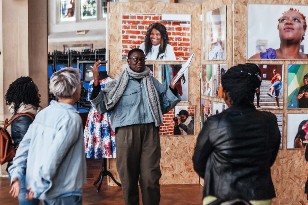 Audience members listening to a talk in an exhibition space.