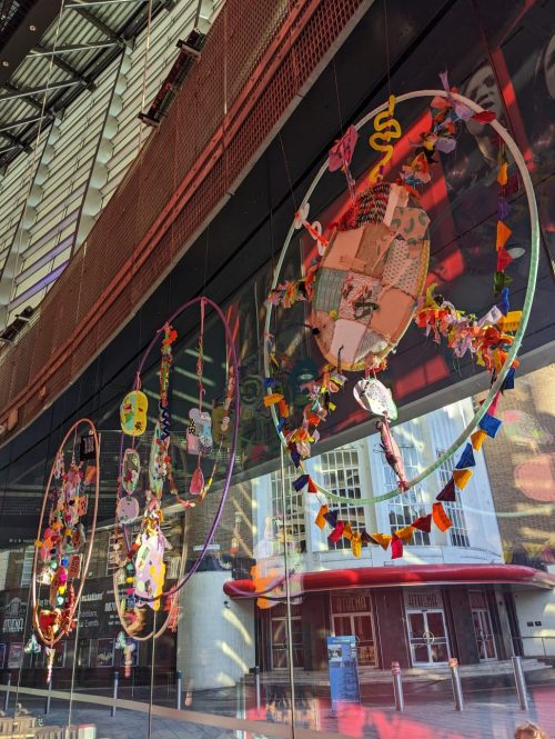 Giant sequins displayed in a window, in three hoops hanging from a balcony.