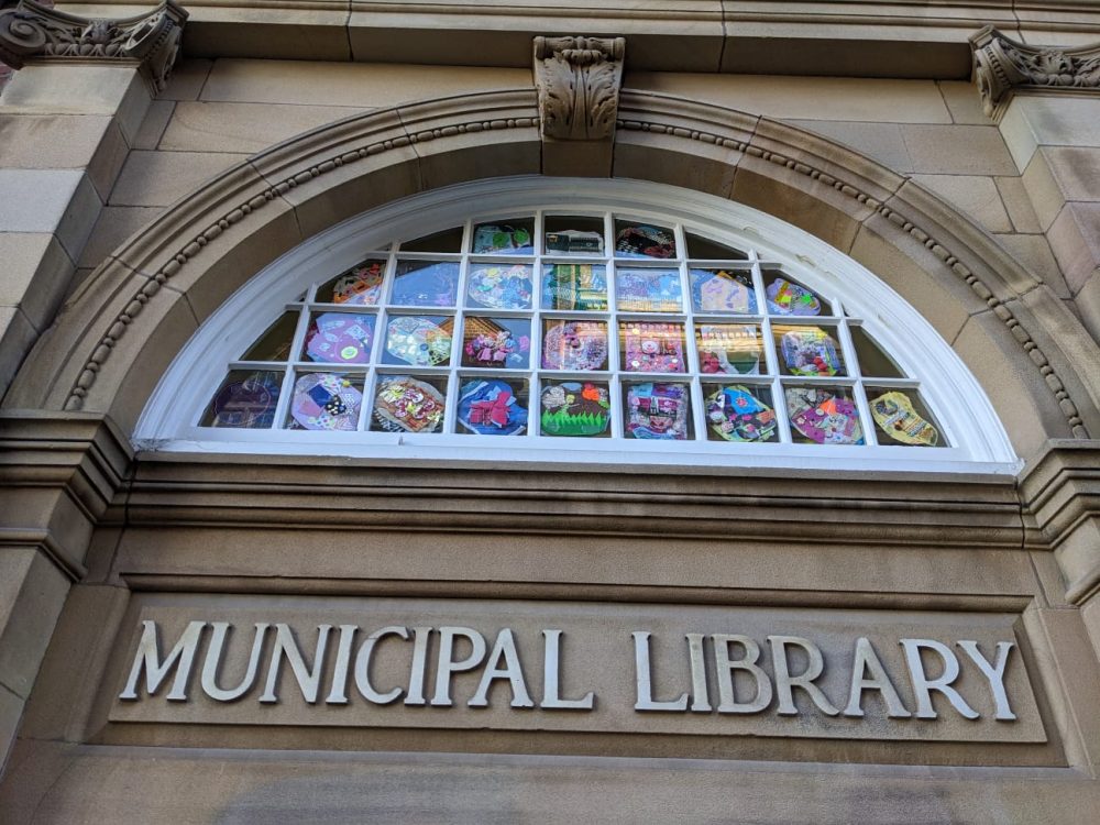 Sequins displayed in a window above the Municipal Library sign.
