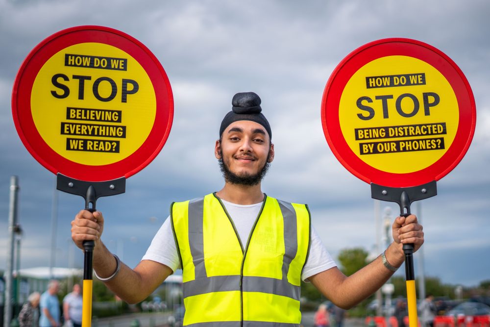 A young person is holding two lollipop signs.