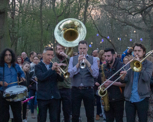 A group of musicians play brass instruments in an outdoor show.